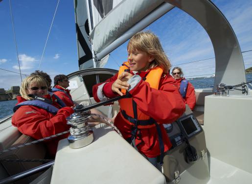 une petite fille à la barre d'un bateau à voiles